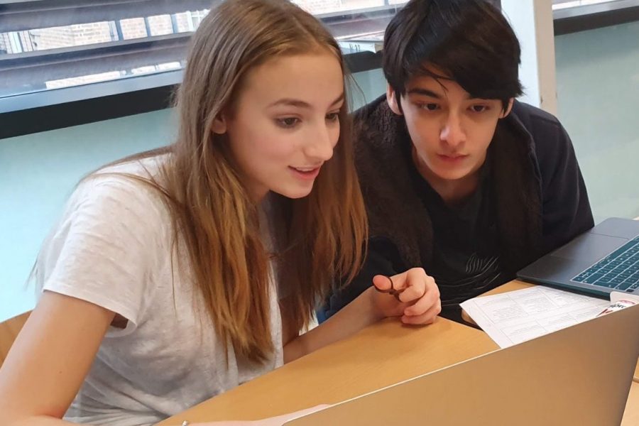 Debate team members Alexis Gerwe (23) and Oliver Presier (23) research current events to prepare for the upcoming debate competition. The debate team will compete against other international schools Nov. 15-16. 