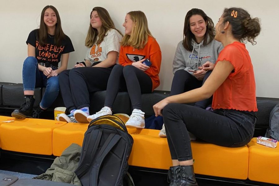Students sit and chat during the Student vs Faculty basketball game, which took place Feb. 12. There are new black and orange bleachers in the Farmer Gym this year which coincided with the days black and orange theme. 