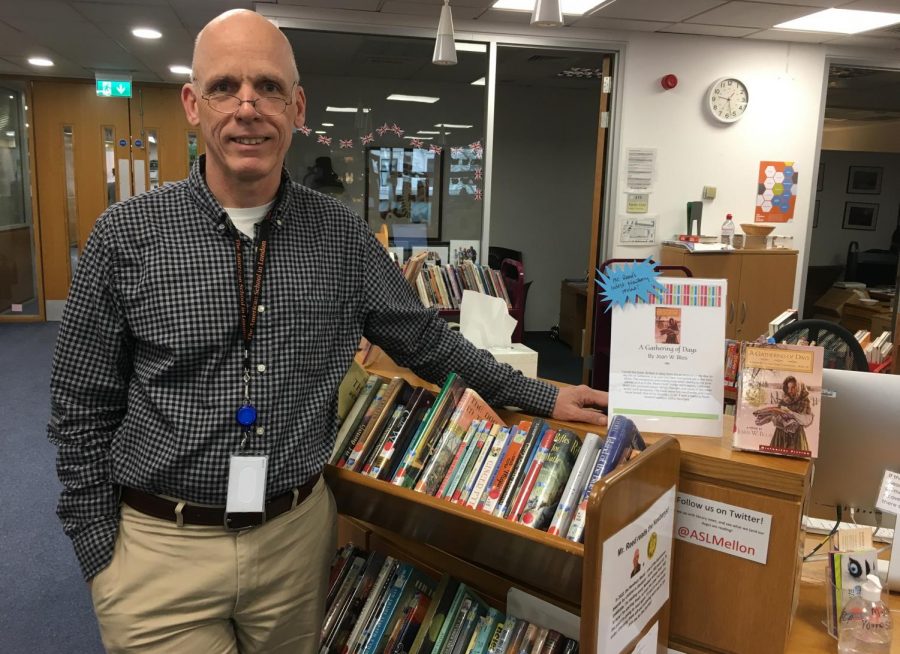 Library Administrative Assistant Steve Reed stands with the bookcase of all the Newbery Medal award winners. Reed has taken on the challenge to read all the winners since the founding of the medal in 1922.
