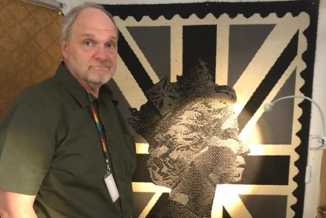 K2 Teacher John O’Toole stands with one of many Queen Elizabeth II poster portraits hung in his classroom. O’Toole attended the Queen’s lying-in-state ceremony Sept. 16 and spent the 10-day mourning period following her death reflecting on previous encounters with the Queen. 
