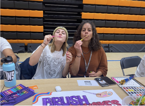 Georgia LaScala (’23), the leader of Brushstrokes and Beats, sits at her club stand Sept. 30 with Science Teacher Alpha Toothman, the faculty sponsor.