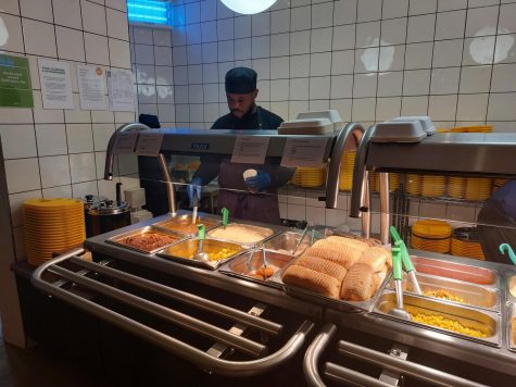 Catering staff member Fidel Mboma prepares to serve lunch Jan. 26. While the cafeteria has adopted various sustainable practices, community members continue to address the issue of food waste.