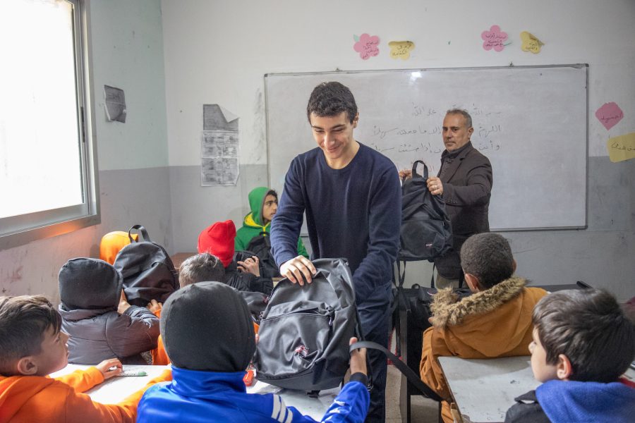 Ojjeh hands out backpacks with educational materials to students in a local school in Mount Lebanon in June of 2022.