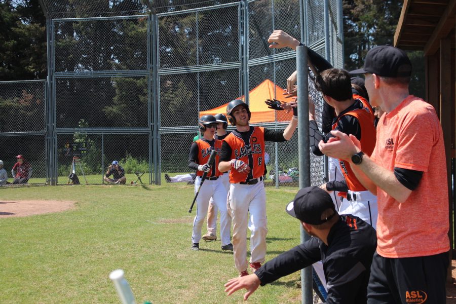 Gideon Putnam (’24) high-fives his varsity boys baseball teammates after a successful run May 27. Putnam said the game against the International School of Brussels went well in a game that they won 17-3.