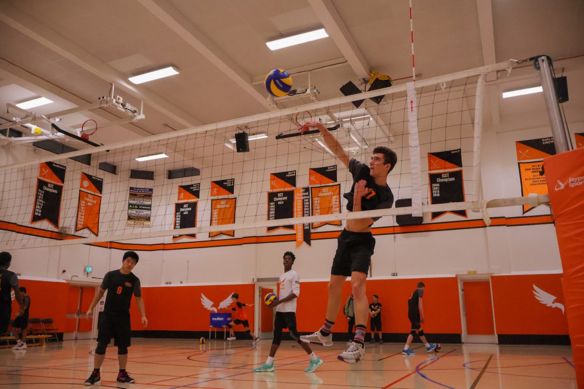 Yifei Yan (’25) watches as Mac John (’26) spikes the ball over the net during warm-ups. The boys varsity volleyball team won against Lynx Volleyball Club 3-0 Oct. 24.
