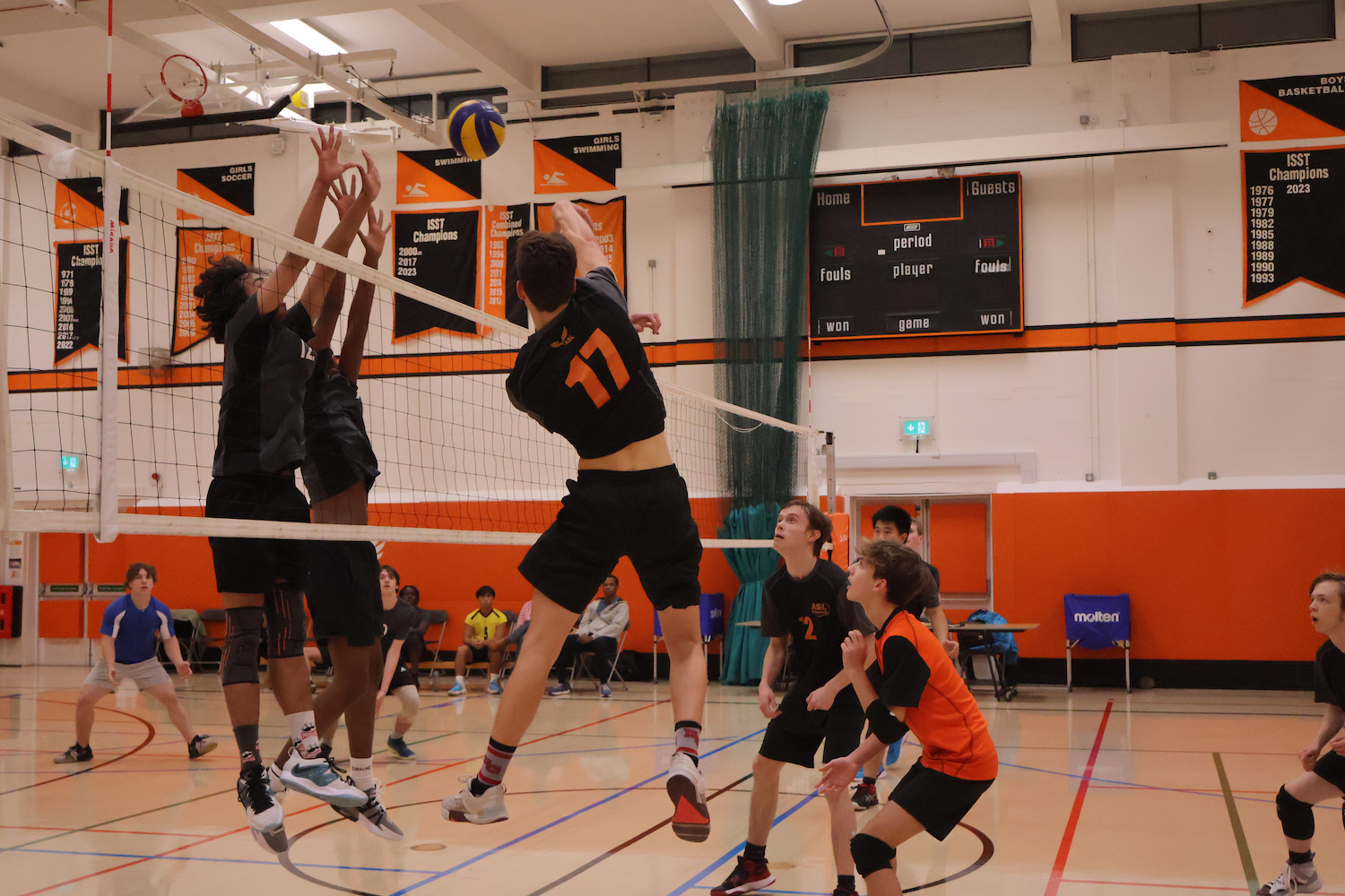 Mac John (26) spikes the ball over the net as the other team jumps to defend Oct. 24. The boys varsity volleyball team won against Lynx Volleyball Club 3-0.