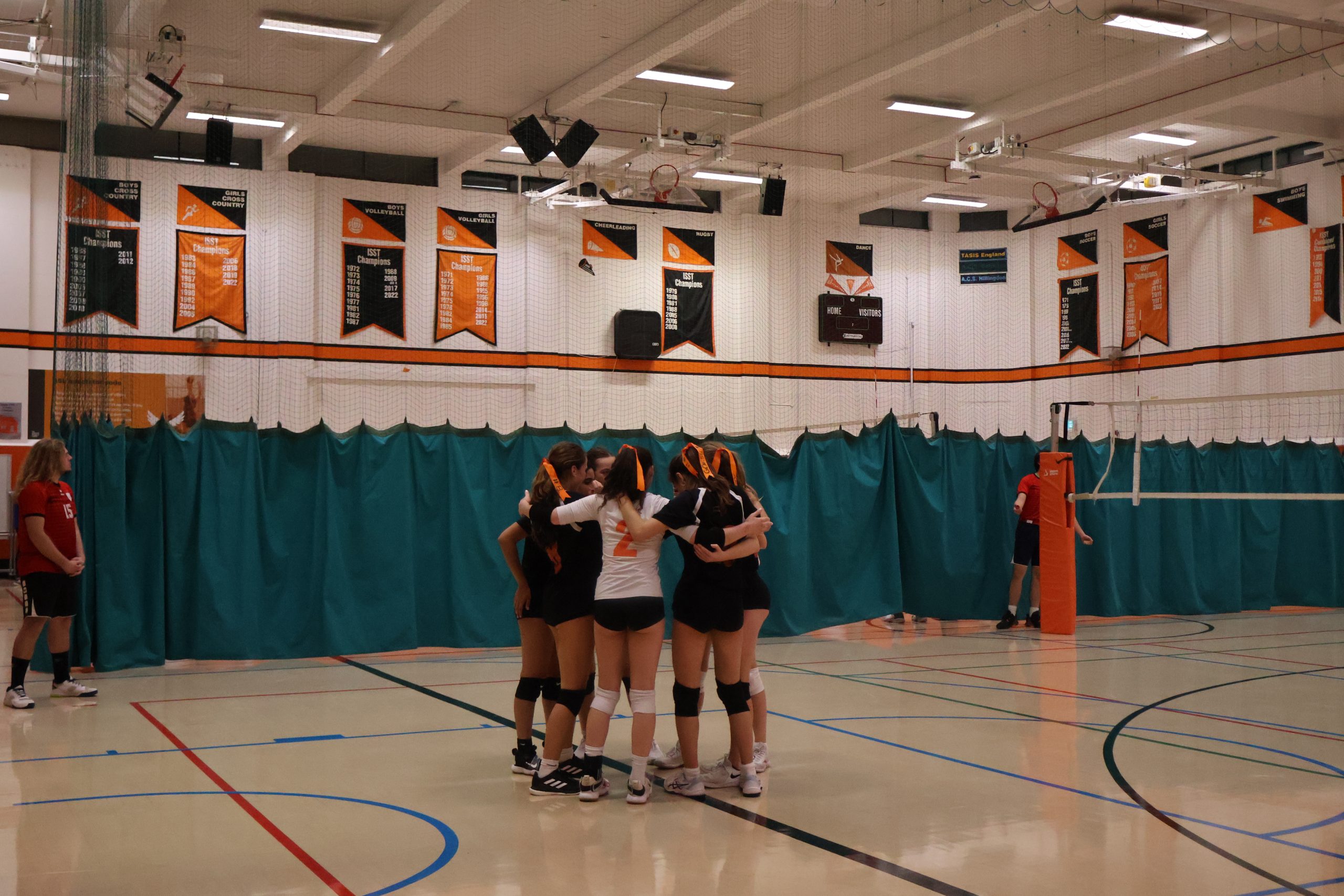 Girls varsity volleyball players hug in a circle as they celebrate winning a point Sept. 29. The team played against the American School of Paris at the London Invitational.