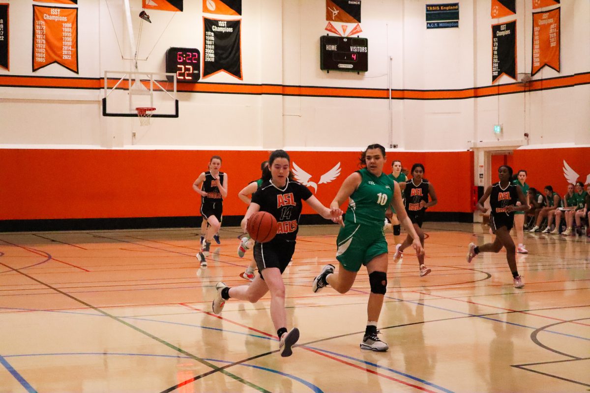 Greta Corrigan (’25) dribbles the ball towards the hoop as an ACS Cobham player attempts to defend. Corrigan was able to make a shot after taking the ball from an ACS Cobham player.